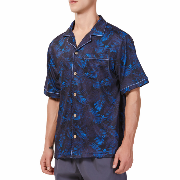 Men's Short sleeve black and blue all over palm frond printed camp shirt in a relaxed fit with a chest pocket made from knit fabric on a model - quarter view