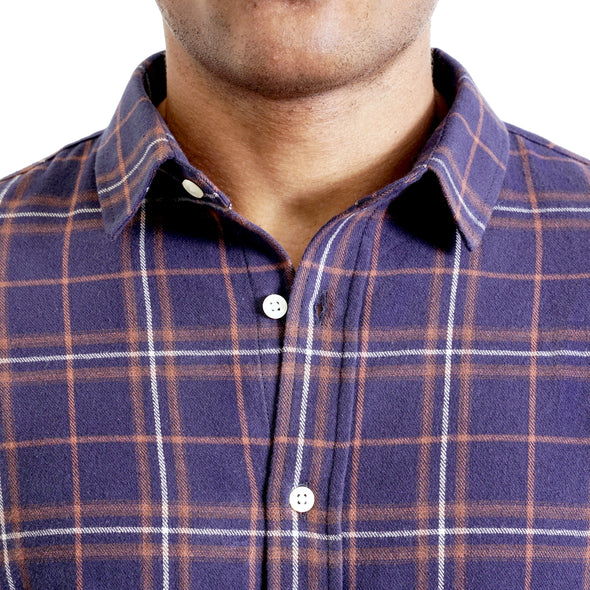 close up view of the pointed collar and neck area of flannel button up shirt in navy plaid on a black male model. The top buttons are undone